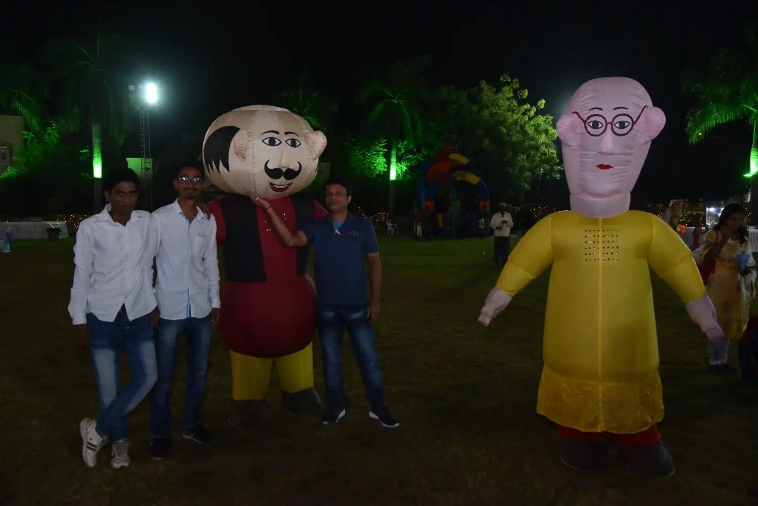 Group of men posing with large cartoon character inflatable figures at night outdoors